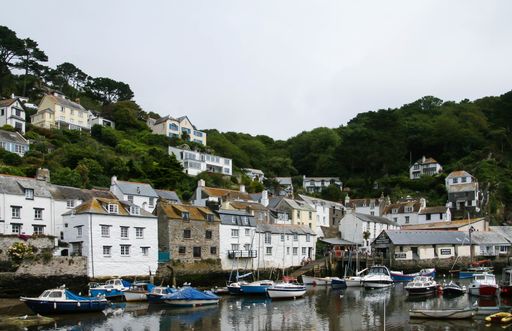 The sailing boats on the water and the houses on a tree-covered hill captured in Polperro Beach, UK