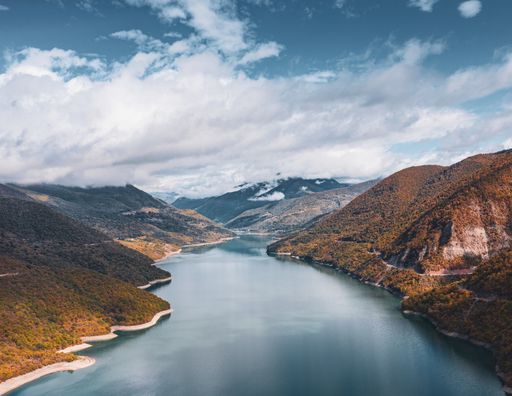 A high angle shot of a river going through the hills under the breathtaking cloudy sky
