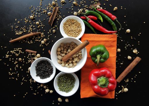 A top view of spices, ingredients, paprika, and cinnamon in white plates on the black table