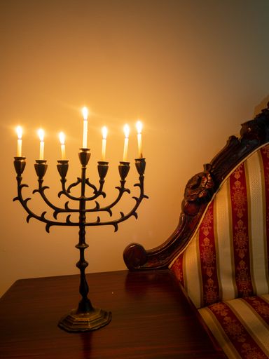 A closeup shot of a seven-branched candelabra with burning candles on the wooden table for Hanukkah