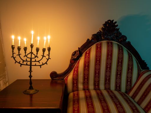 A closeup shot of a seven-branched candelabra with burning candles on the wooden table for Hanukkah
