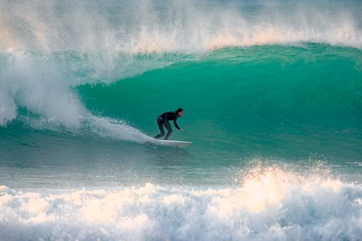 A surfer riding a big wave in Cornwall