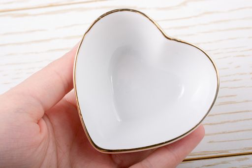 A closeup shot of a small heart-shaped ceramic plate in a human hand