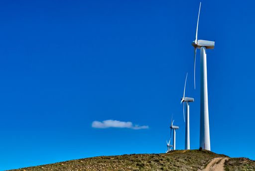 A low angle shot of wind turbines under a blue sky
