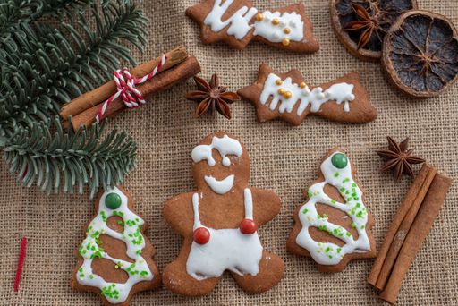 A top view of delicious gingerbread cookies next to cinnamon sticks and pine leaves on a burlap