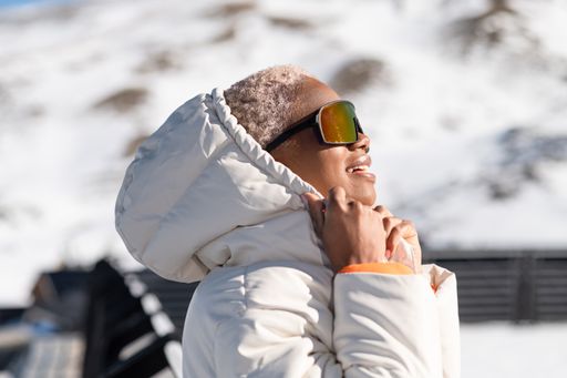 A closeup of the young African American woman in snow goggles and a white down jacket.