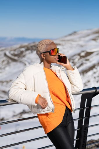 A vertical closeup of the young African American woman talking on the phone at a winter resort.