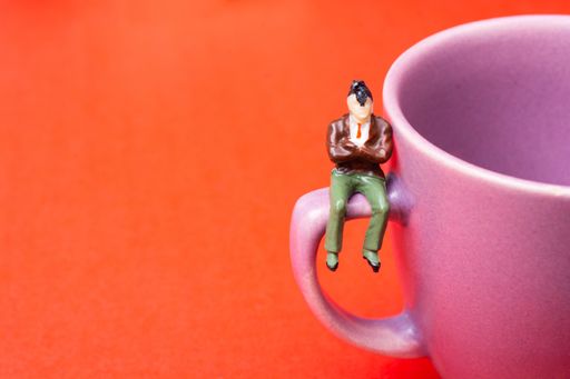A closeup shot of a pink cup with a male figure on it isolated on the orange background