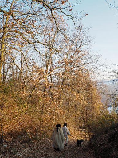 A vertical shot of a young African American female and her mother in a fur coat walking in a park