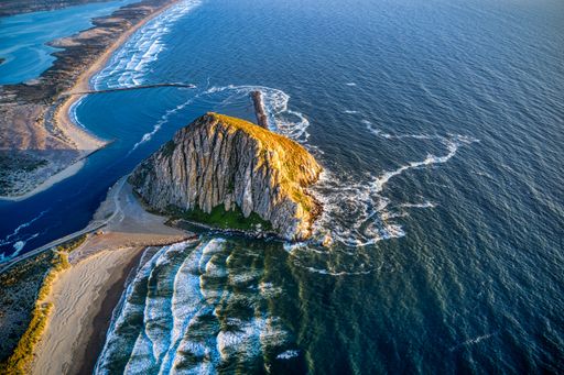 An aerial shot of the Morro Rock in California at sunset