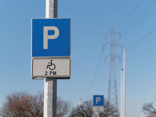 Close-up shot of a handicapped parking sign attached on a pole against a blue sky