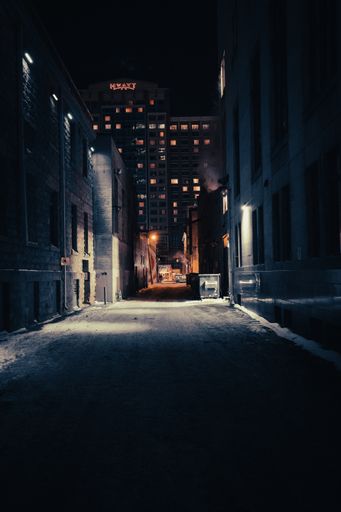 A vertical shot of a dark alley with the Hyatt Hotel at the end in Calgary, Alberta, Canada