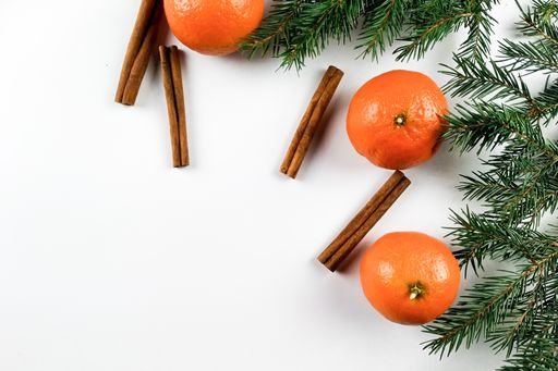 A holiday background with cinnamon sticks, tangerines, and pine tree branches