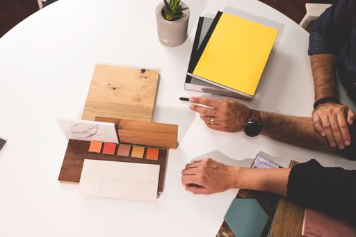 A close-up shot of hands on the table during an office presentation displaying some materials for an interior design