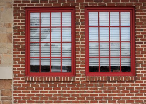 A closeup shot of windows with red frames on a brick wall