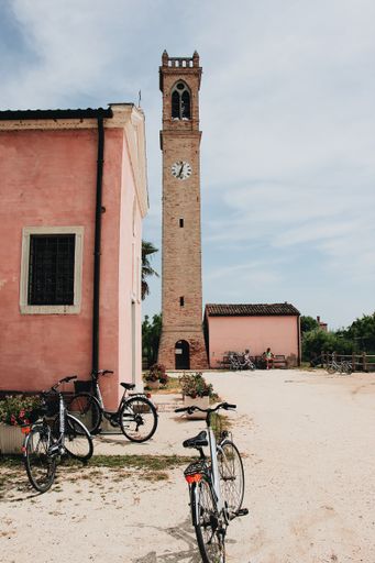 A vertical shot of two bicycles parked near old historic buildings during daytime