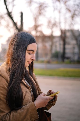 A vertical shot of a girl looking at her phone in a park