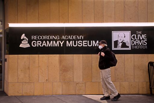 Pedestrian in Coronavirus surgical mask passing the Recording Academy's Grammy Museum in downtown Los Angeles
