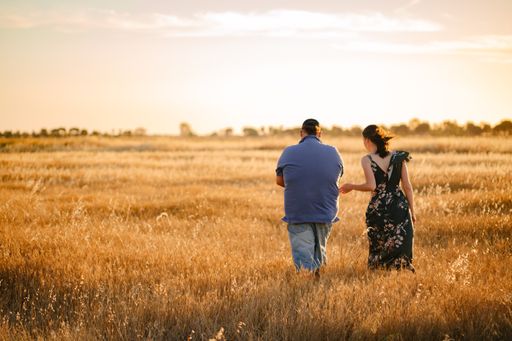 A closeup of a couple walking in a field