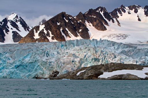 The scenic Svalbard landscape composed of rocky mountain, glacier and still waters in Norway under