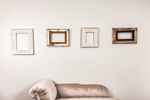 The empty wooden picture frames on a plain white wall for decor purposes