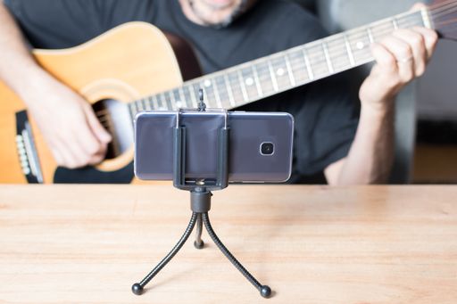 A shallow focus of a smartphone with which a person is having a guitar lesson by video call