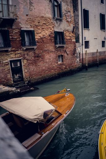 A vertical picture of old colorful buildings next to the boat on the Grand Channel in Venice, Italy