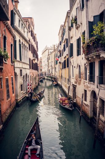 A vertical picture of gondolas on the grand channel between colorful buildings in Venice, Italy