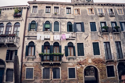A low angle shot of an old Italian building with unique architecture and colorful laundry