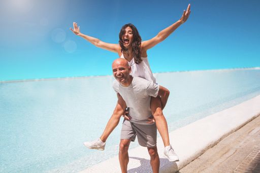 A middle-aged Hispanic couple laughing and playing lovingly on the beach