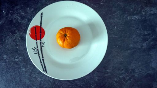 A top view of a ripe juicy orange in a white dish on a blue background