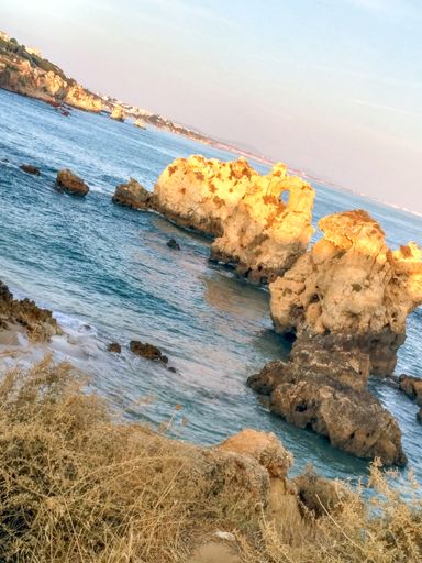 A vertical shot of a seashore with huge cliffs at sunrise