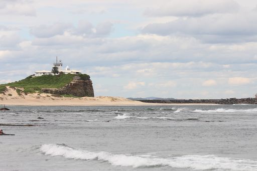 A beautiful view of the Nobbys Lighthouse by weaker side against a blue cloudy sky in Australia