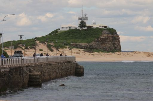 A beautiful view of the Nobbys Lighthouse by weaker side against a blue cloudy sky in Australia
