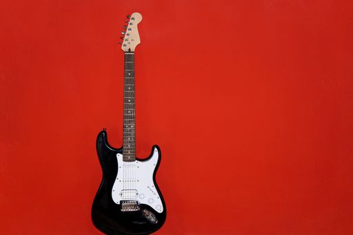 Isolated black and white electric guitar on red background, copy space
