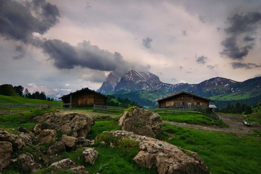 A landscape of old wooden barns surrounded by rocky hills in the evening in South Tyrol, Italy