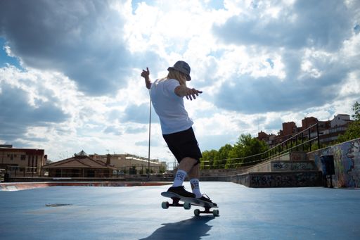 A young professional skateboarder performing skate in the skatepark against a cloudy sky