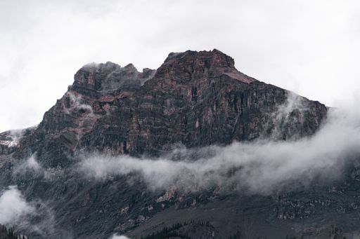 A landscape of rocky mountains covered in the fog under a cloudy sky in Yoho National Park, Canada