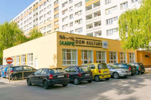 A Parked cars in front of the culture club Dom Kultury close by an apartment block in the Stare Zegrze district
