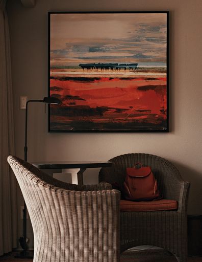 A vertical shot of the interiors of a house including the armchairs, picture and lamp