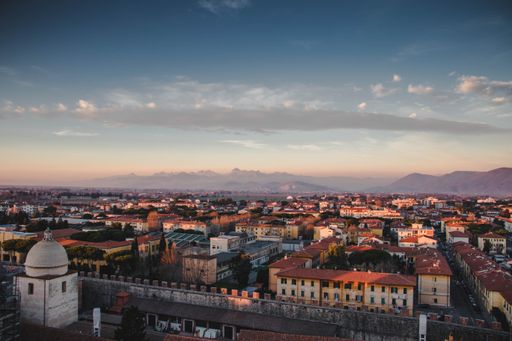 A cityscape of Pisa under a cloudy sky during the sunset in Italy