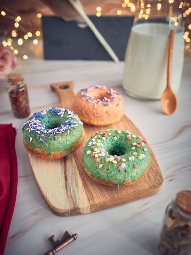 A vertical shot of colorful donuts on a wooden tray on a decorated table
