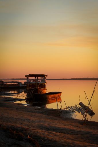 A vertical shot of old boats in a lake with the sunset sky in the background