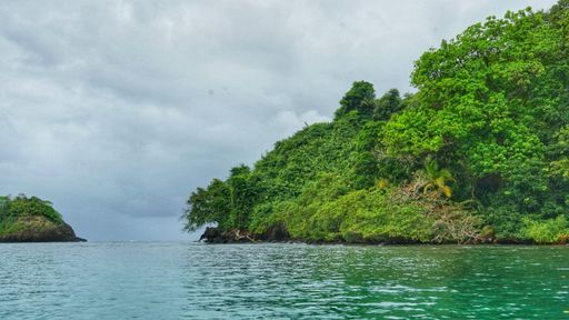 A scenic view of the shores of green Caribbean islands under the cloudy sky