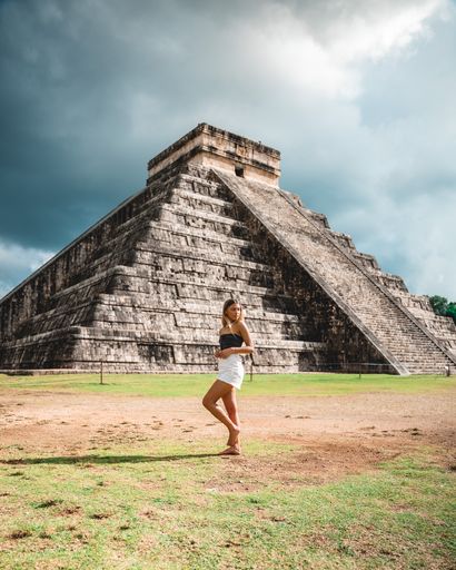 A vertical shot of a young caucasian female standing against the Chichen Itza, Mexico