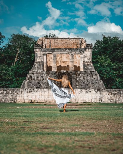 A vertical shot of a young caucasian female standing against the Chichen Itza, Mexico