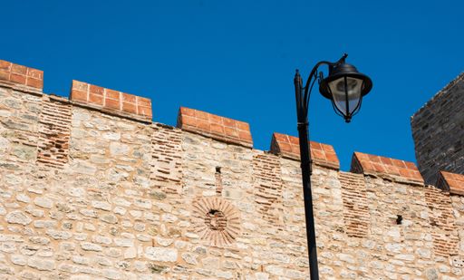 A low angle shot od a city light and an old building made of rocks captured on a sunny day