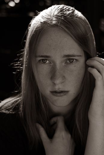 A vertical shot of a young Caucasian girl posing while looking away from the camera