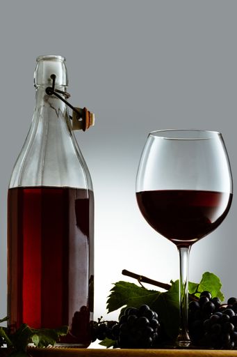 A vertical shot of elegant crystal glass filled with red blackberry wine, isolated on white