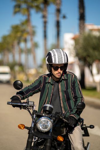 A closeup of a man with a motorcycle posing in stylish clothes